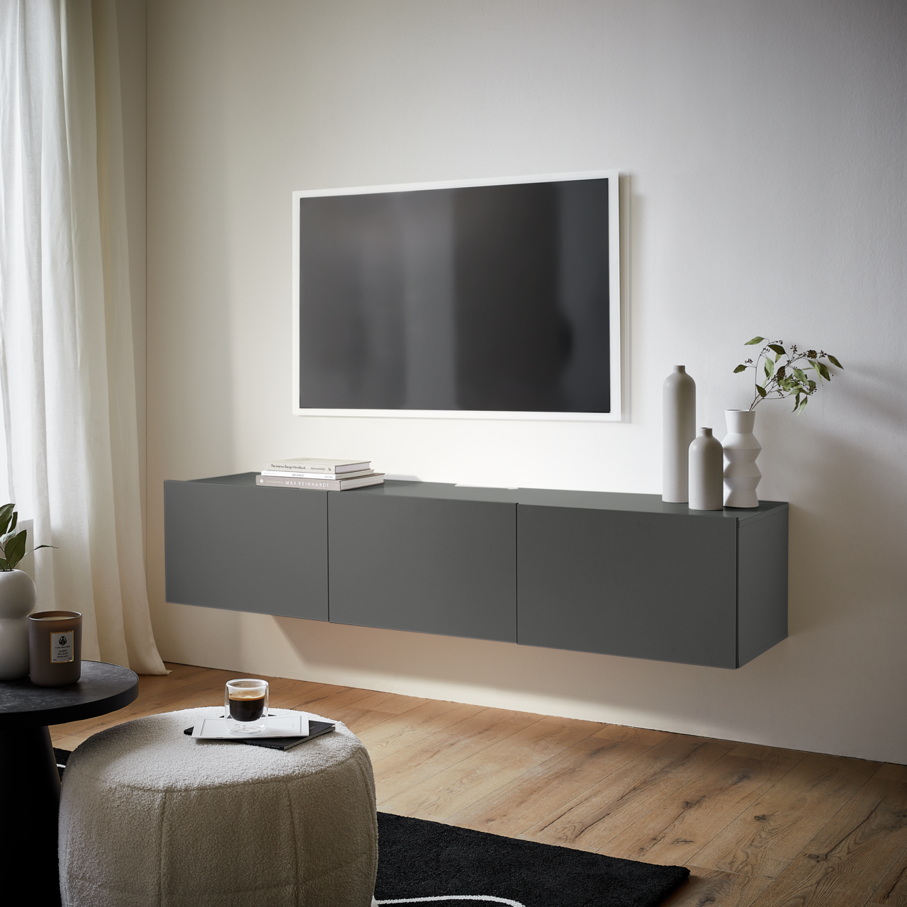 Modernes, graues TV-Hängelowboard in einem stilvollen Wohnzimmer, seitliche Perspektive.