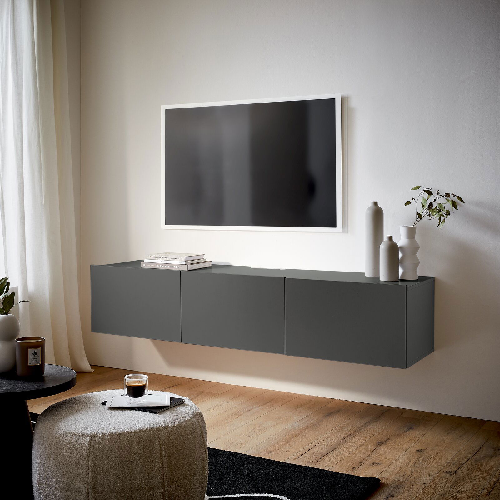 Modernes, graues TV-Hängelowboard in einem stilvollen Wohnzimmer, seitliche Perspektive.