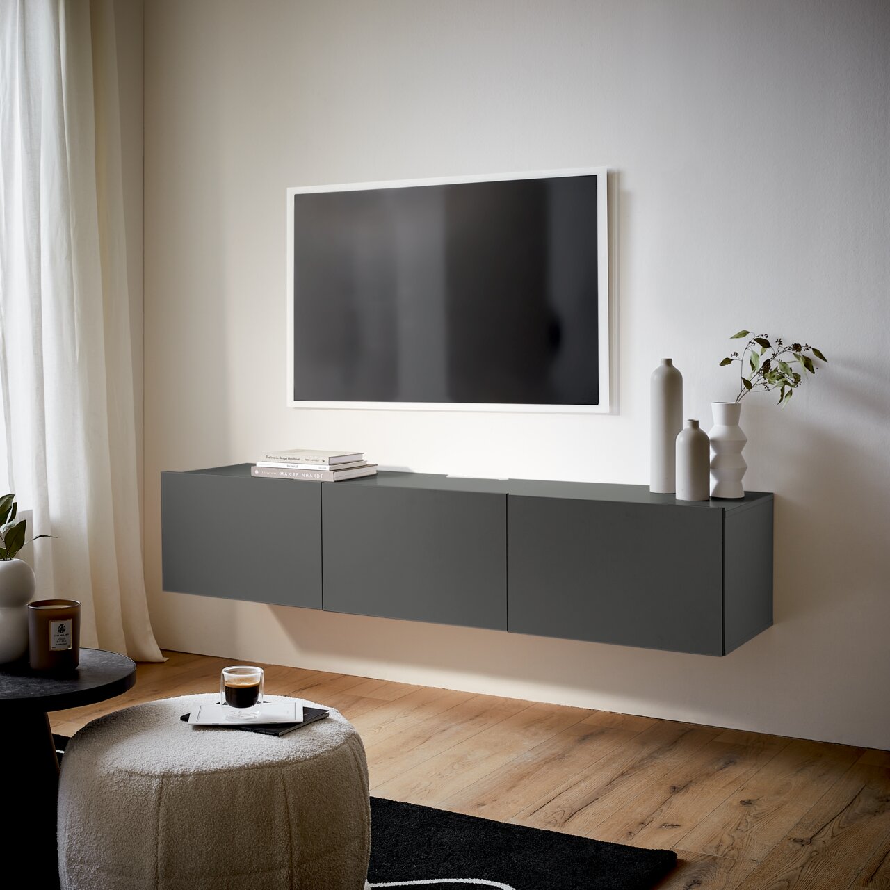 Modernes, graues TV-Hängelowboard in einem stilvollen Wohnzimmer, seitliche Perspektive.