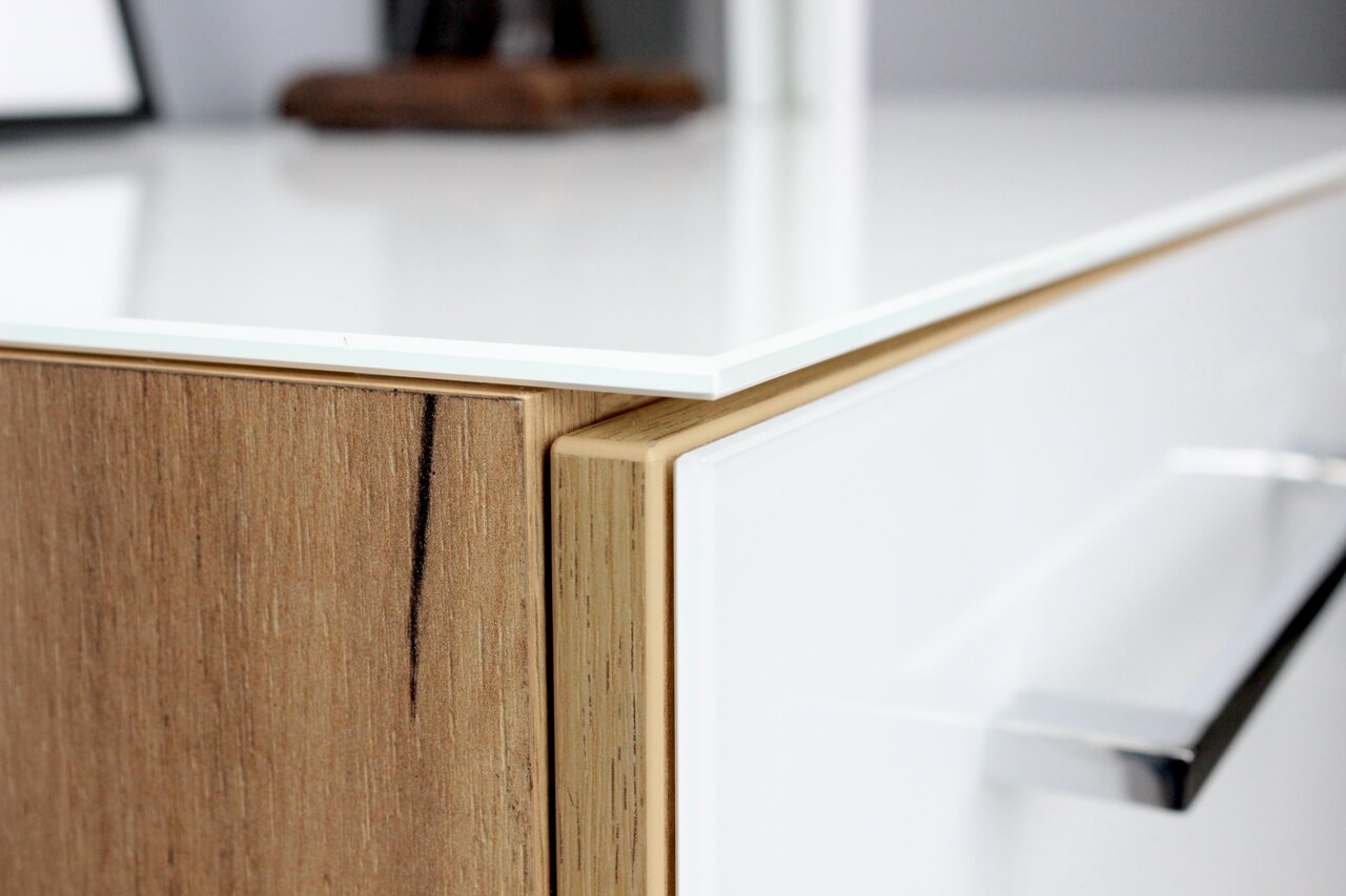 Nahaufnahme eines modernen Aktenschranks mit Holz- und Weißglas-Elementen, seitliche Perspektive.
