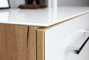 Nahaufnahme eines modernen Aktenschranks mit Holz- und Weißglas-Elementen, seitliche Perspektive.