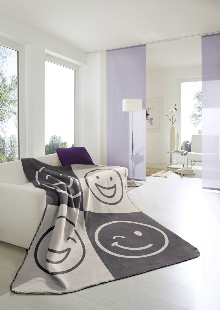 Woonkamerdeken 150 x 200 cm met vrolijke gezichten in een moderne woonkamer, gezien van voren.