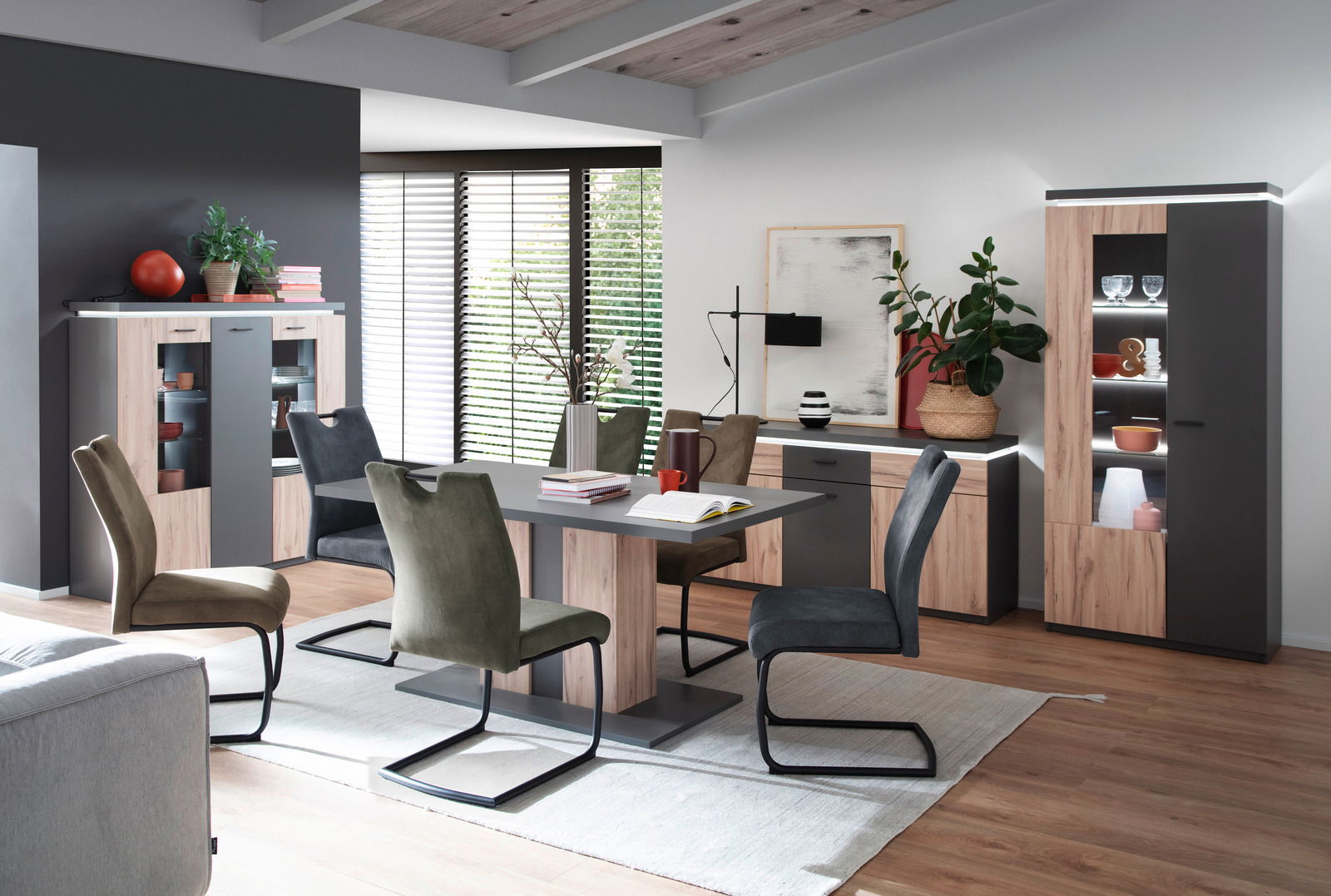 Moderne Esszimmermöbel in einem stilvollen Raum mit Esstisch, Stühlen, Vitrinen und Sideboard, seitliche Perspektive.