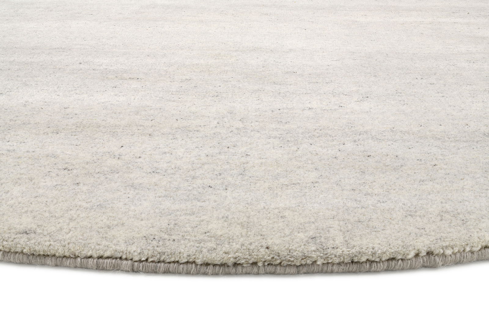 Nahaufnahme eines runden, hellen Wollteppichs mit weicher Textur.