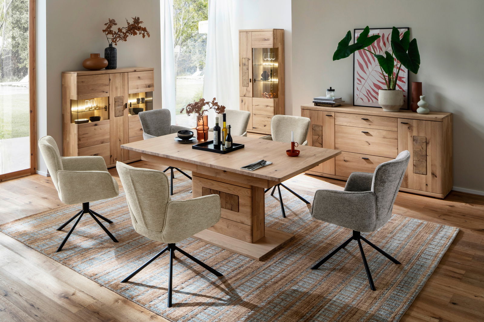 Esszimmer mit Holztisch und sechs gepolsterten Stühlen, umgeben von Vitrinen und Sideboard aus Holz, aus der Perspektive eines diagonalen Blicks auf den Tisch.