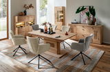 Esszimmer mit Holztisch und sechs gepolsterten Stühlen, umgeben von Vitrinen und Sideboard aus Holz, aus der Perspektive eines diagonalen Blicks auf den Tisch.