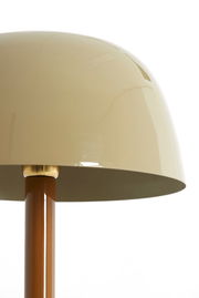 Nahaufnahme einer Tischleuchte mit einem glänzenden, beigen Lampenschirm und einem braunen Ständer, seitliche Perspektive.