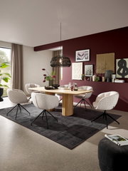 Modernes Esszimmer mit rechteckigem Holzesstisch und fünf gepolsterten Drehstühlen auf dunklem Teppich, darüber schwarze Pendelleuchte, Perspektive: leicht erhöhte Frontansicht schräg von links