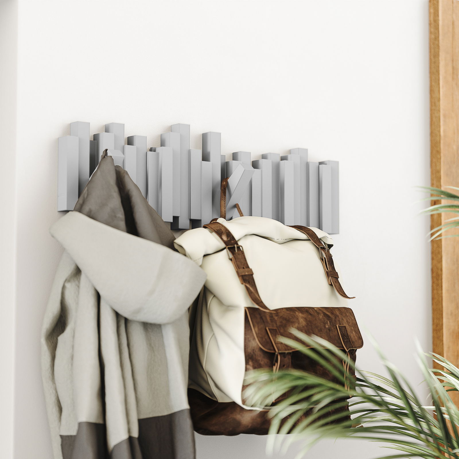 Moderne Wandgarderobe mit geometrischem Design, von der Seite fotografiert, mit aufgehängtem Mantel und Rucksack.