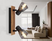 Moderner Strahler mit zwei verstellbaren Leuchten, montiert auf einer Holzplatte, seitliche Perspektive im Wohnzimmer.