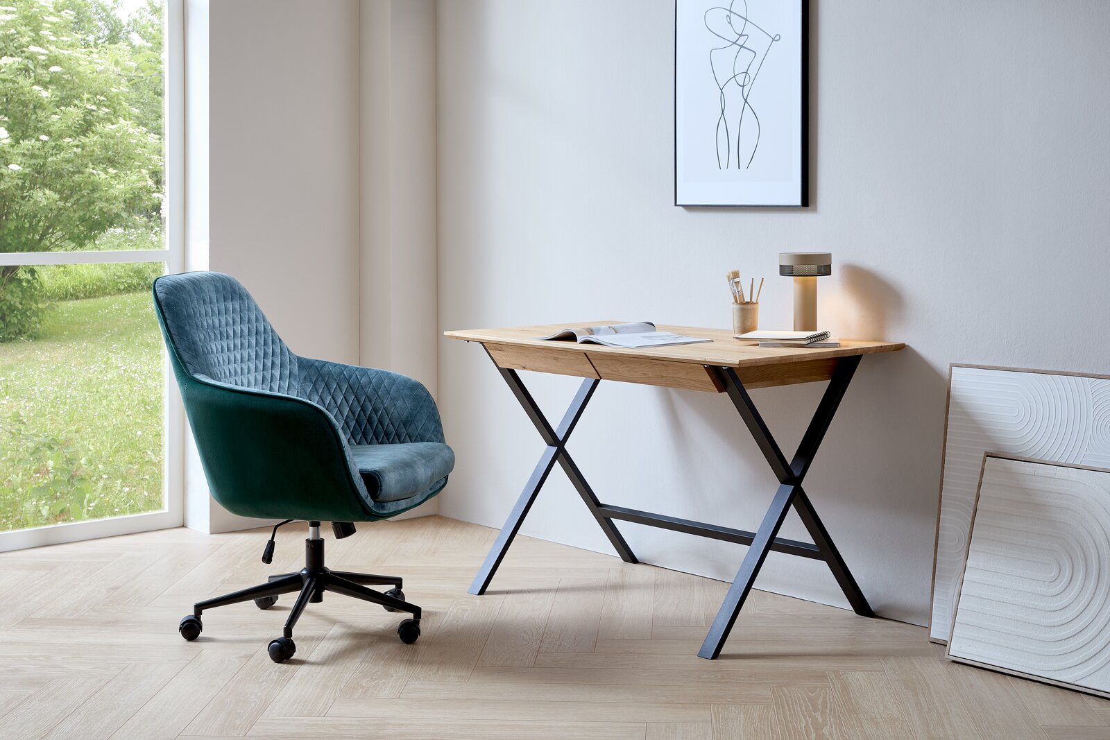 Moderner Drehstuhl in Grün mit gestepptem Muster, seitliche Perspektive, neben einem Schreibtisch mit Holzplatte und Metallbeinen in einem hellen Raum mit großem Fenster.