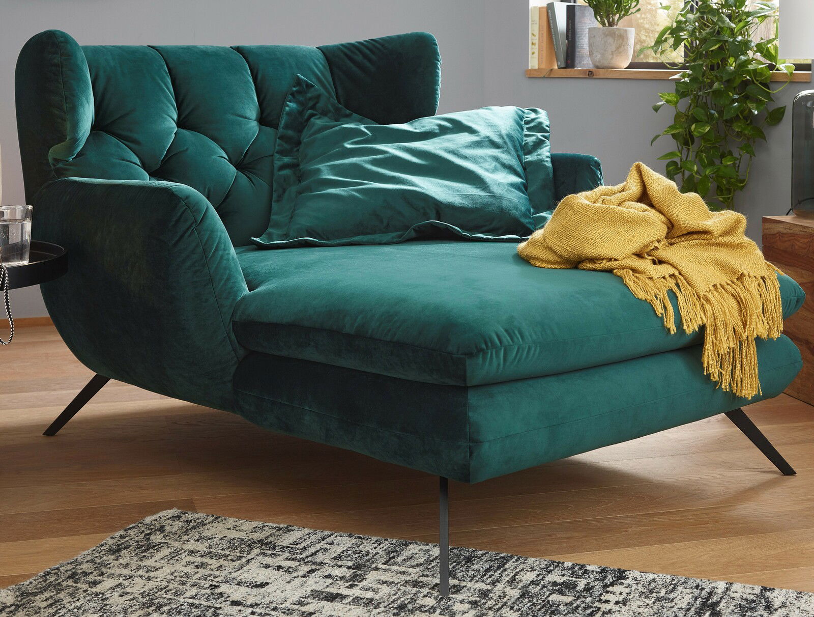 Grünes Longseat mit Kissen und gelber Decke, seitliche Perspektive