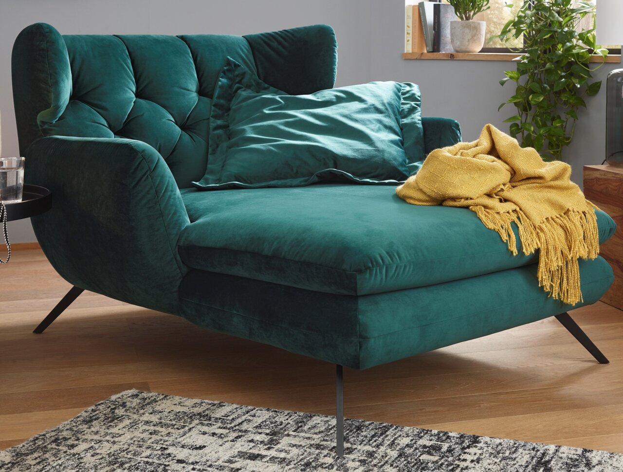 Grünes Longseat mit Kissen und gelber Decke, seitliche Perspektive