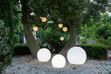 Kugelleuchten BULY 50 in einem Garten, auf dem Boden und hängend an Bäumen, bei Dämmerung aus der Perspektive von vorne betrachtet.