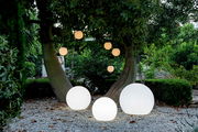 Kugelleuchten BULY 50 in einem Garten, auf dem Boden und hängend an Bäumen, bei Dämmerung aus der Perspektive von vorne betrachtet.