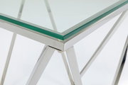 Nahaufnahme eines modernen Beistelltisches mit Glasplatte und verchromtem Metallgestell, Perspektive von der Ecke.