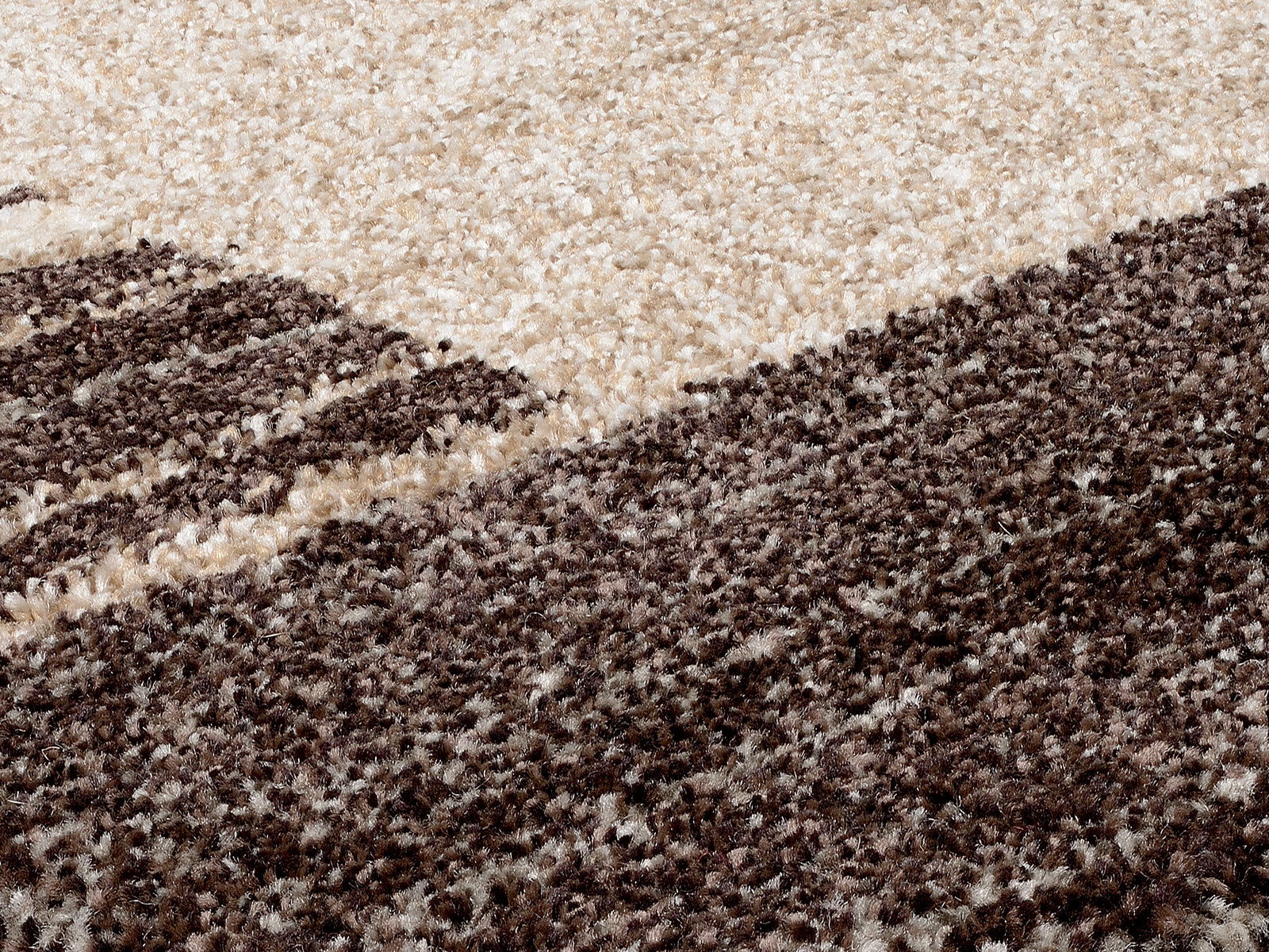 Nahaufnahme eines strukturierten Teppichs in Creme- und Brauntönen, perspektivisch von der Seite aufgenommen.