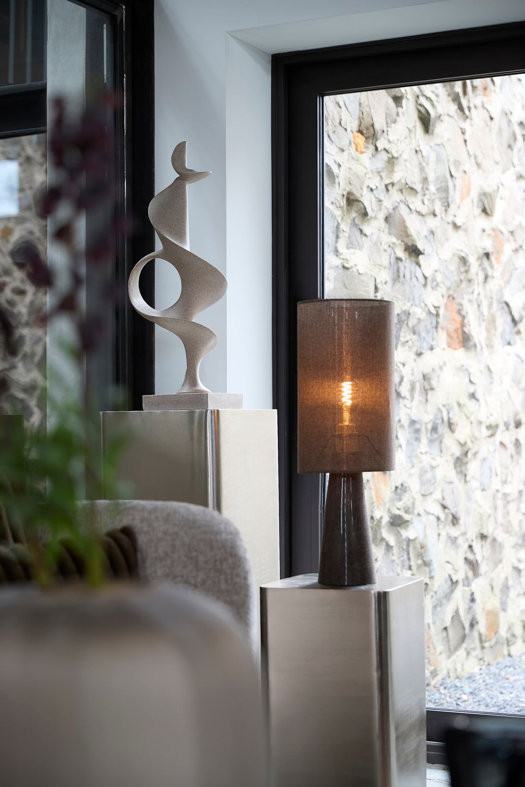 Moderne Skulptur auf einer metallischen Säule in einem stilvollen Innenraum, seitliche Perspektive.