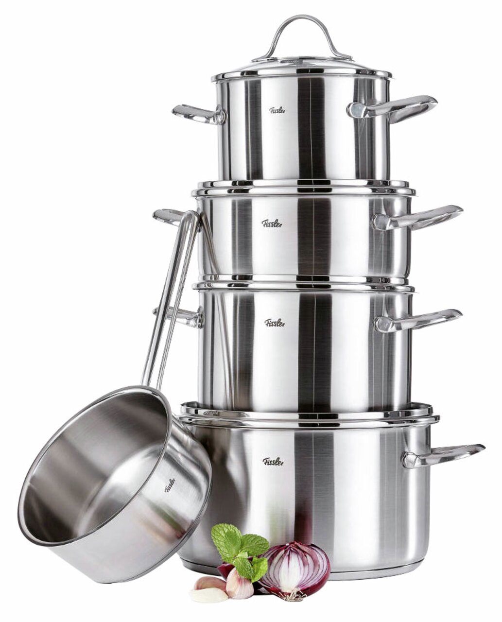 Fissler Topfset 5-tlg. PARIS Stapel von glänzenden Edelstahl-Töpfen mit Deckel, seitliche Perspektive, umgeben von frischen Zutaten wie Zwiebeln und Knoblauch.