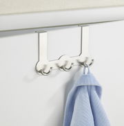 Edelstahl Türgarderobe Rondo mit vier Haken, frontal an einer Tür montiert, mit einem blauen Handtuch.