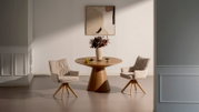 Ronde houten eettafel met conische voet, gefotografeerd frontaal op ooghoogte, met twee beige gestoffeerde draaistoelen met houten poten in een minimalistische ruimte