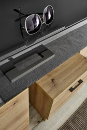 Nahaufnahme eines modernen Garderoben-Sets mit Holzschubladen und schwarzer Glasoberfläche, auf der eine Sonnenbrille liegt. Perspektive von oben.