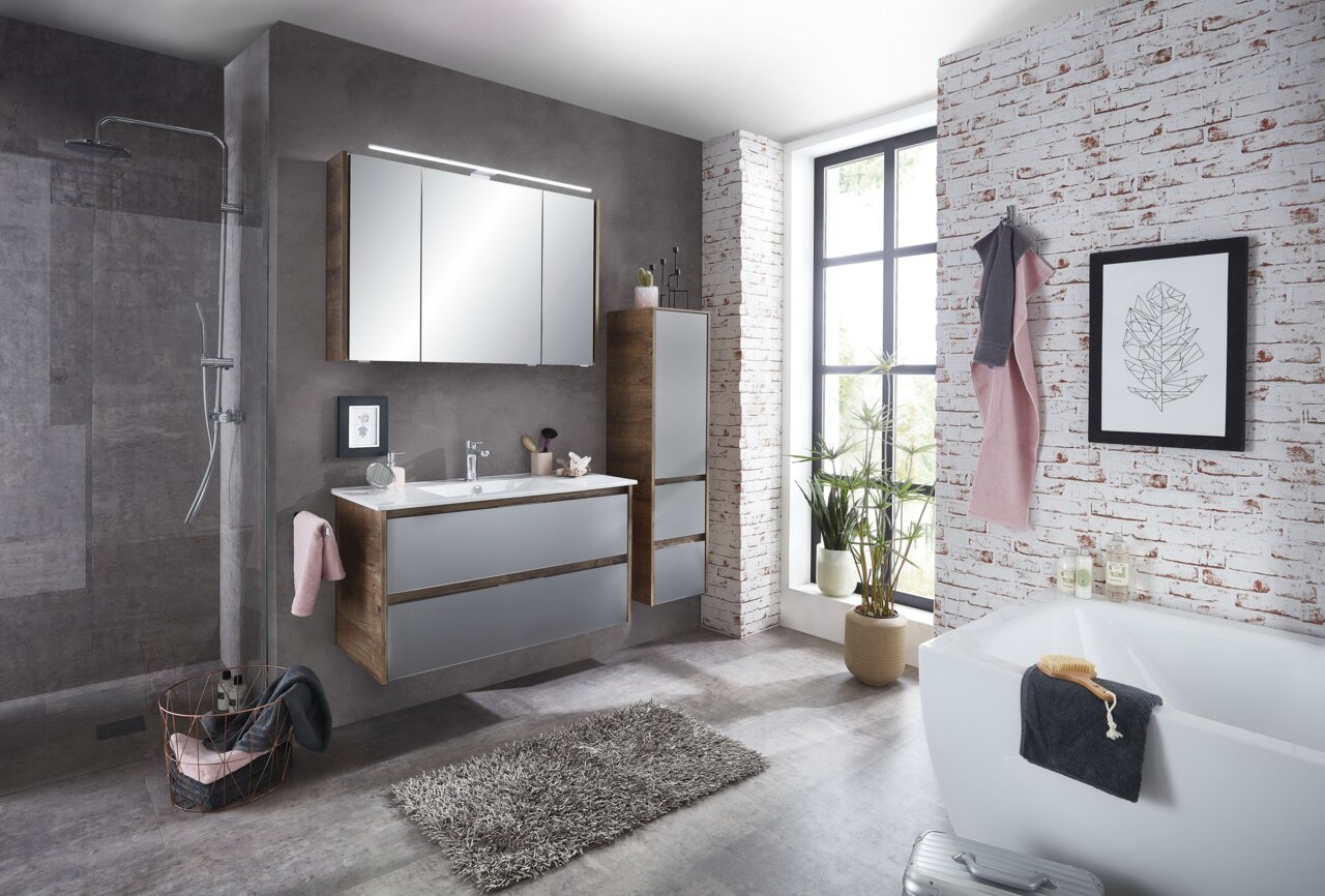 Moderne Badkombination mit Spiegel, Waschbecken und Stauraum in einem stilvollen Badezimmer mit Ziegelwand und Pflanzen, seitliche Perspektive.