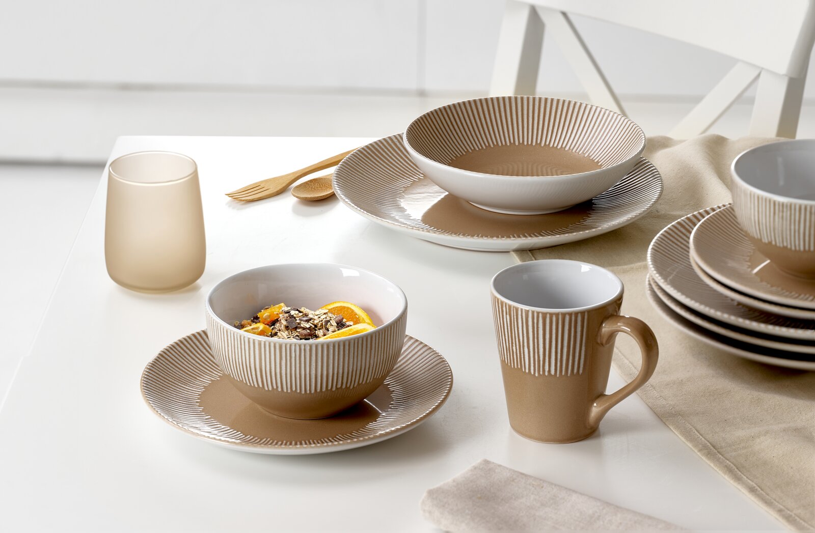 Beige serviesset van 18-delig met schalen, kopjes en borden in een modern streepmotief, zijaanzicht van een gedekte tafel.