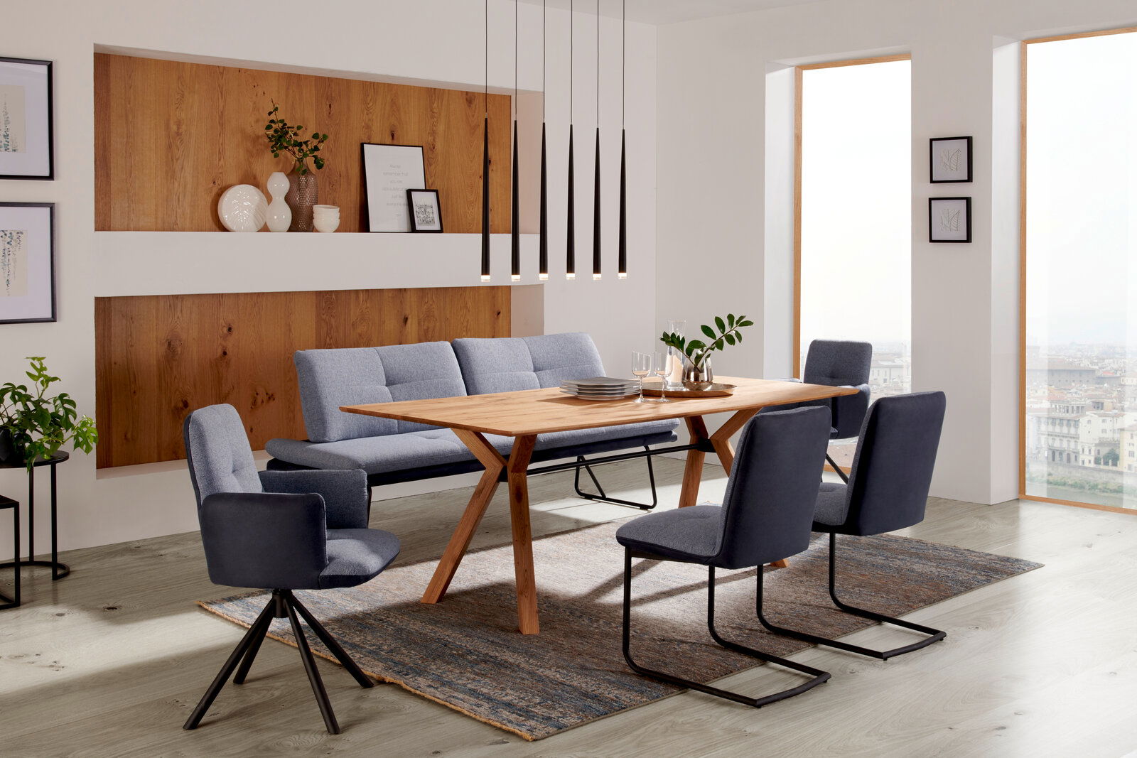 Moderner Essbereich mit einem Esstisch aus Holz und blauen Stühlen, seitliche Perspektive.