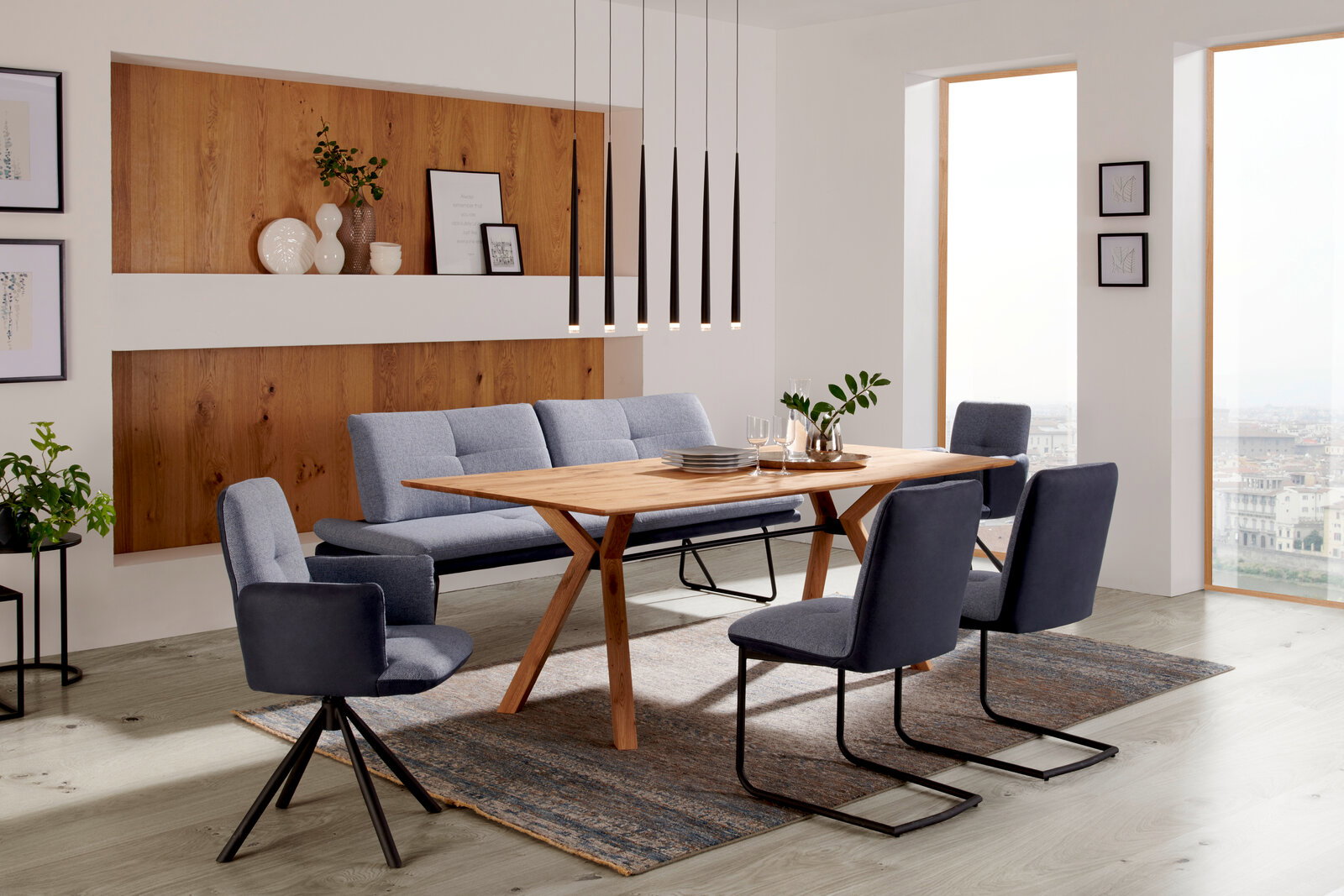 Moderner Essbereich mit einem Esstisch aus Holz und blauen Stühlen, seitliche Perspektive.
