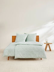 Satinbettwäsche 155x220cm in sanftem Grün mit dezentem Muster, auf einem Bett mit Holzrahmen, seitliche Perspektive