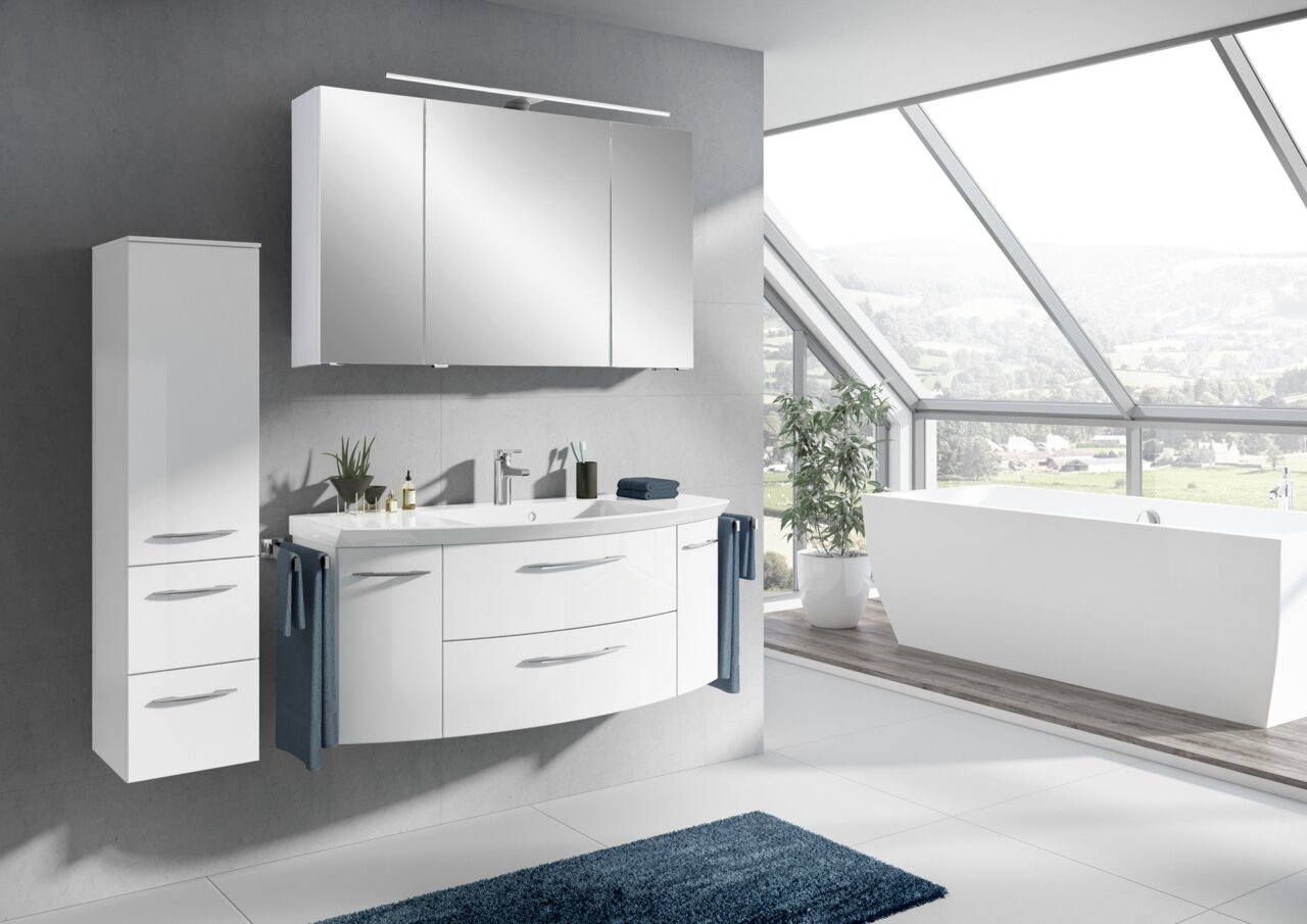 Moderne Badkombination mit weißem Waschtisch, Spiegelschrank und Hochschrank in einem hellen Badezimmer mit Panoramafenster, seitliche Perspektive.