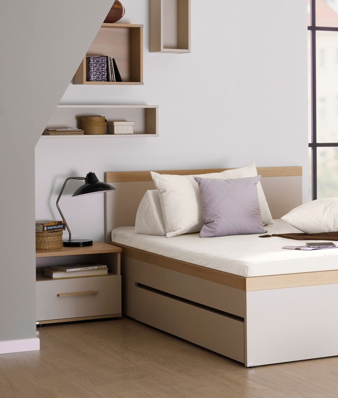 Paidi Nachtkommode MALIO Nachtkommode in einem modernen Schlafzimmer, seitliche Perspektive, neben einem Bett mit Kissen und einer Lampe.