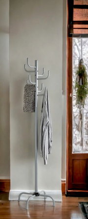 Silberner freistehender Garderobenständer aus Metall mit mehreren Haken, im Innenraum vor heller Wand neben Holztür, fotografiert in frontaler Perspektive auf Augenhöhe.