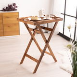 Holz-Serviertablett mit Standfuß, seitliche Perspektive, dekoriert mit Tassen und einem Stück Kuchen, in einem hellen Raum mit Holzboden.