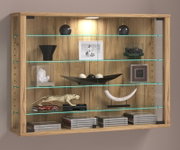 Wandhängende Vitrine aus Holzoptik mit Glasböden und integrierter LED-Beleuchtung, dekoriert mit Vasen, Schalen, Büchern und CDs, frontal aus leichter Untersicht fotografiert.