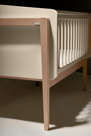 Nahaufnahme eines Anstellbetts aus Holz mit seitlichen Gitterstäben, seitliche Perspektive