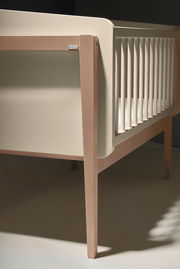 Nahaufnahme eines Anstellbetts aus Holz mit seitlichen Gitterstäben, seitliche Perspektive