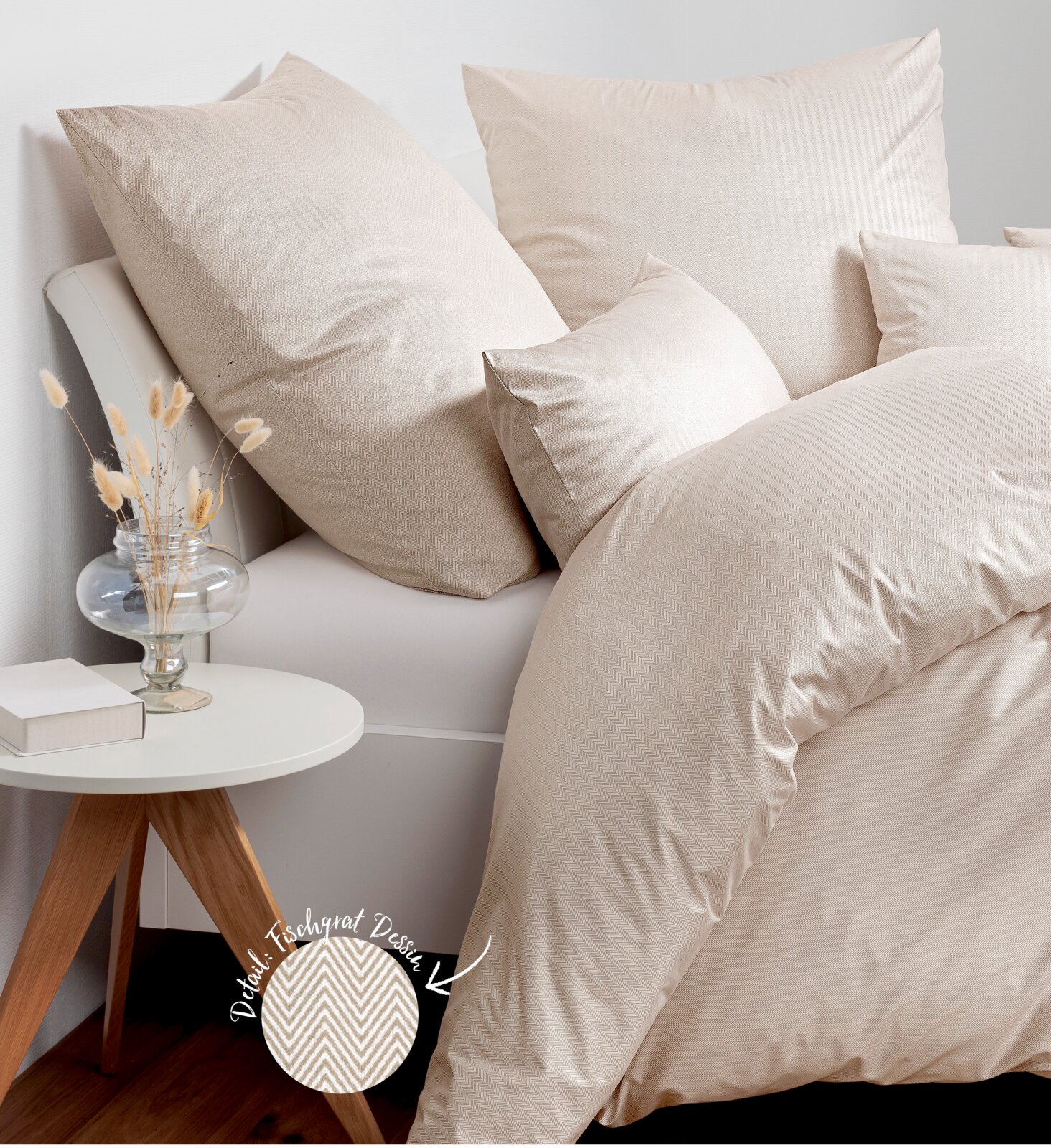 Beige Bettwäsche-Set auf einem Bett, bestehend aus Kissen und Decke, mit Fischgratmuster. Perspektive von der Seite.