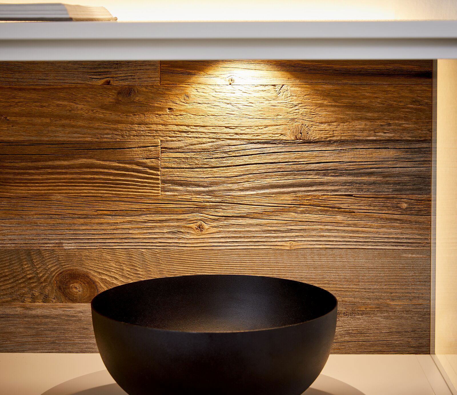 Nahaufnahme eines Sideboards mit Holzrückwand und schwarzer Schale, von vorne betrachtet.