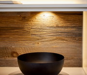 Nahaufnahme eines Sideboards mit Holzrückwand und schwarzer Schale, von vorne betrachtet.