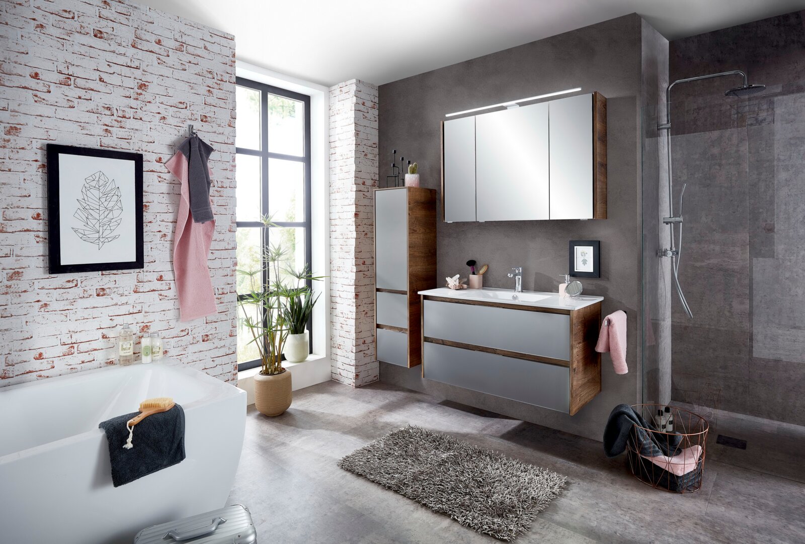 Modernes Badezimmer mit Midischrank in Holzoptik, grauen Fronten und Spiegel, seitliche Perspektive.