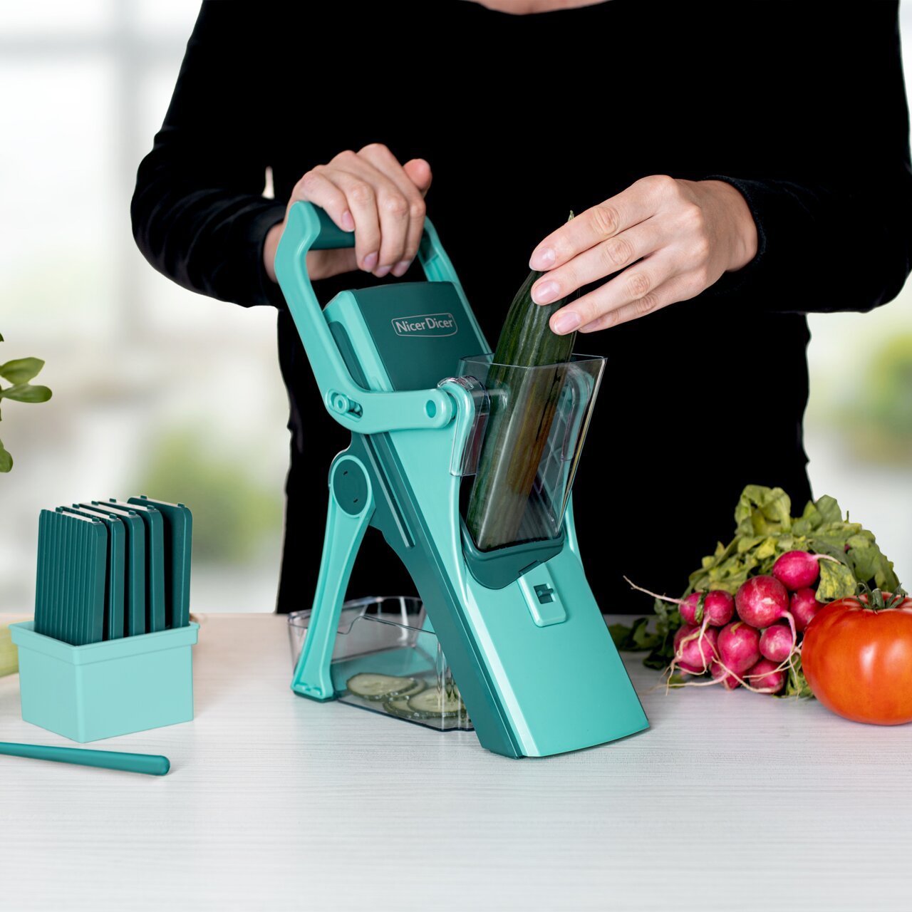 Een vrouw gebruikt de Nicer Dicer Mando, 10-delige set, om een komkommer te snijden, zijaanzicht