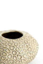 Close-up van een decoratieve theelichthouder met een gestructureerd oppervlak in beige, gezien van bovenaf.