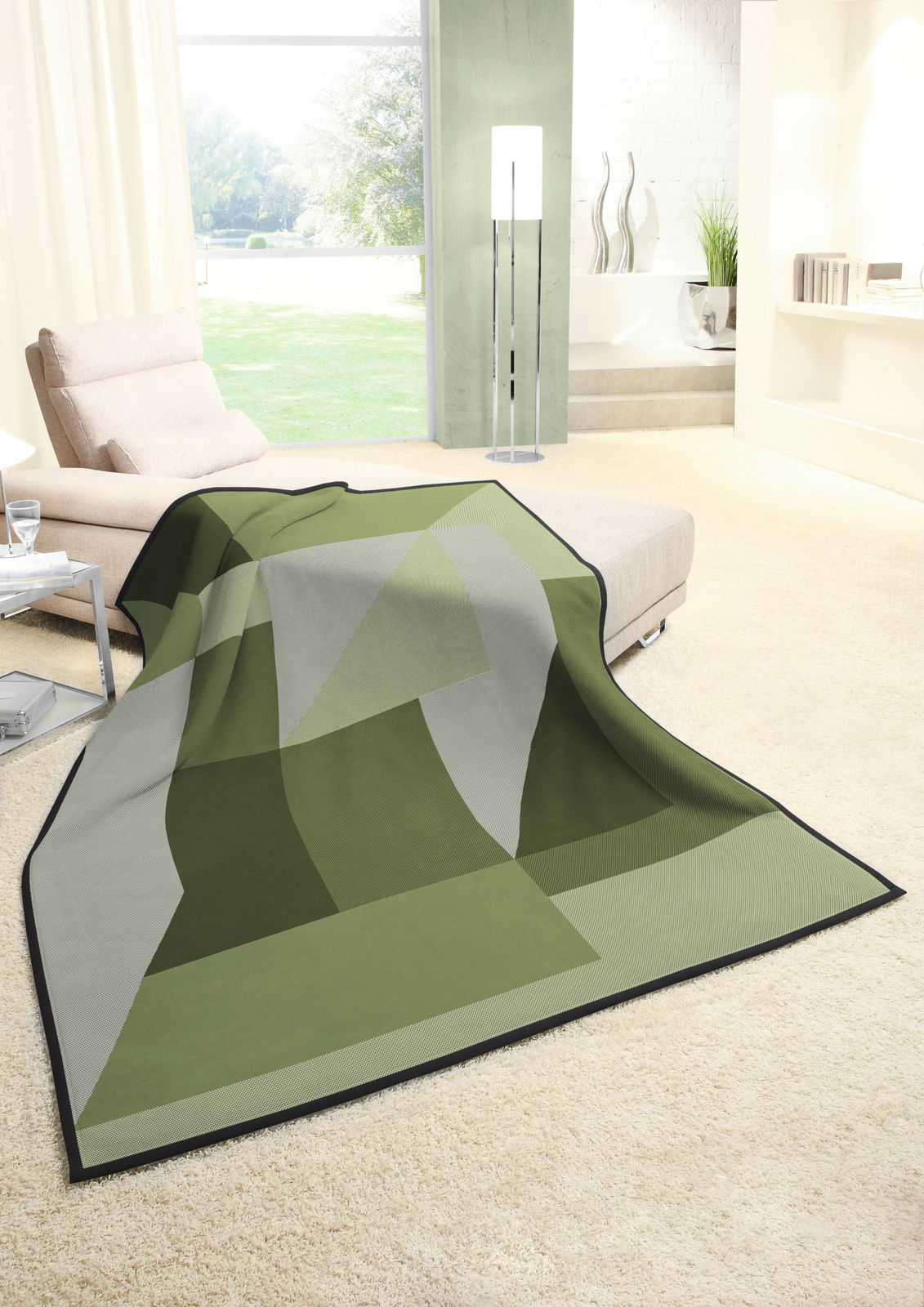 Grüne Wohndecke mit geometrischem Muster auf einem cremefarbenen Teppich in einem modernen Wohnzimmer, seitliche Perspektive.