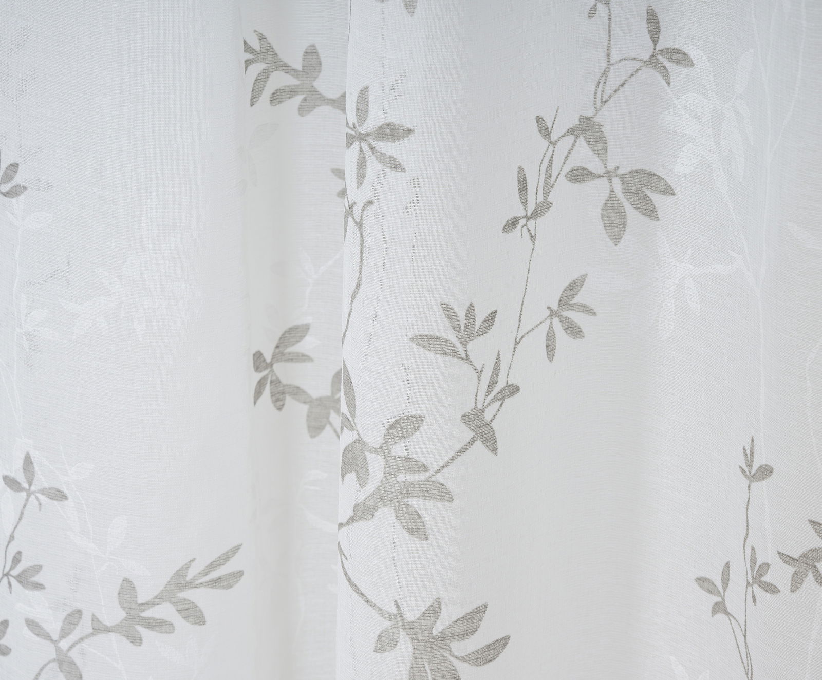 Nahaufnahme eines weißen Vorhangs mit grauem Blattmuster, Perspektive von vorne
