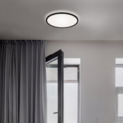 Moderne LED-Deckenleuchte in einem Raum mit geöffneter Tür und Vorhängen, von unten betrachtet.