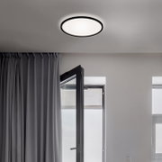 Moderne LED-Deckenleuchte in einem Raum mit geöffneter Tür und Vorhängen, von unten betrachtet.