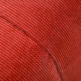 Nahaufnahme eines roten, gerippten Stoffes, vermutlich Teil eines Hockers, aus seitlicher Perspektive.