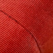Nahaufnahme eines roten, gerippten Stoffes, vermutlich Teil eines Hockers, aus seitlicher Perspektive.